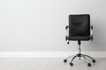 Comfortable office chair near light wall indoors. Space for text