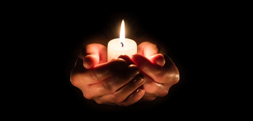Burning candle in woman hands over black. Religious christmas spa and wellness concept