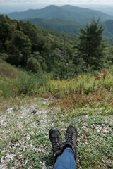 Hiking boots in front of a landscape view of mountains and greenery on blue ridge parkway