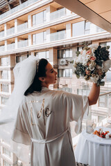 Portrait of the bride with a wedding bouquet. Wedding preparations. Morning on the balcony.
