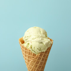 Delicious ice cream in waffle cone on light blue background, closeup