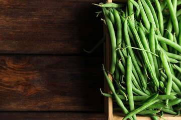 Fresh green beans in crate on wooden table, top view. Space for text