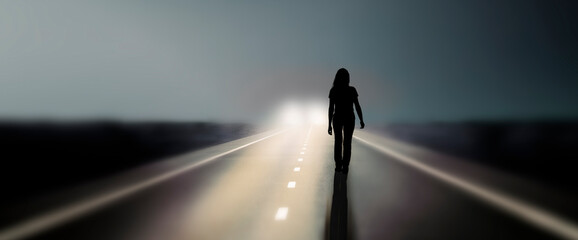 Silhouette einer Frau auf einer Straße im Scheinwerferlicht