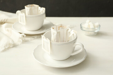 Cup with drip coffee bag on white wooden table