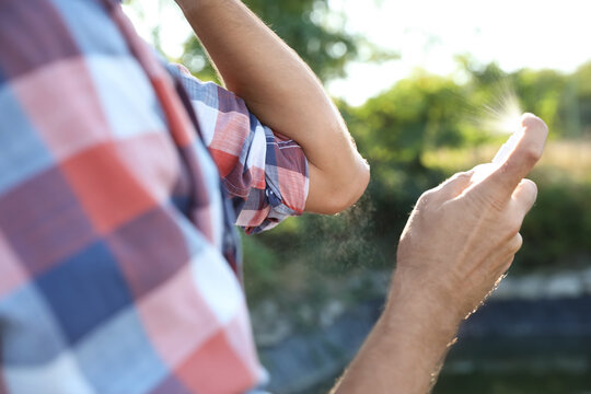 Man Applying Insect Repellent Onto Arm Outdoors, Closeup