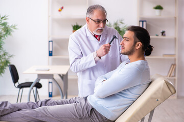 Young sick man visiting old doctor otolaryngologist