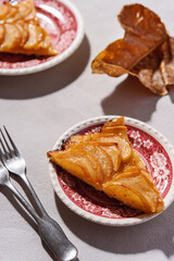 Slices of Homemade French Apple Tart or Pie on plates on light concrete background