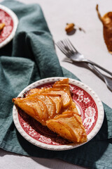 Slices of Homemade French Apple Tart or Pie on plates on light concrete background