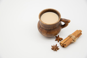 Obraz na płótnie Canvas Brown clay mug with a drink and various spices on a white background.