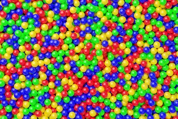 Ball pool or pit filled with red, green, yellow and blue plastic balls, abstract texture background top view flat lay from above