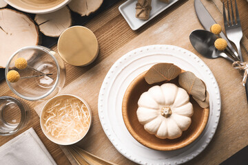 Fototapeta na wymiar Autumn table setting with pumpkin and decor on wooden background, flat lay