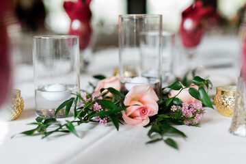 Beautiful Roses in a Garland on a centerpiece with floating candles in a clear glass vase in the background