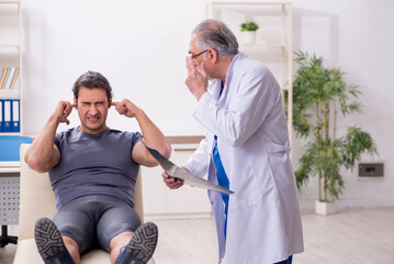 Obraz premium Young male athlete visiting old doctor radiologist