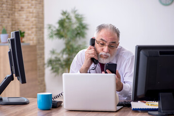 Old male boss sitting at desktop in the office