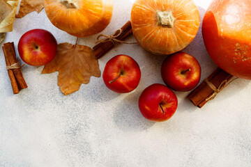 Red apples and pumpkins with dry leaves and cinnamon on white background