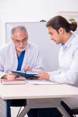 Experienced doctor dentist teaching young male assistant