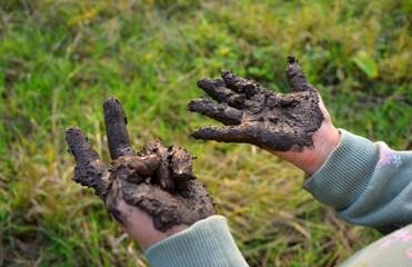 Girl showing muddy hands outdoors