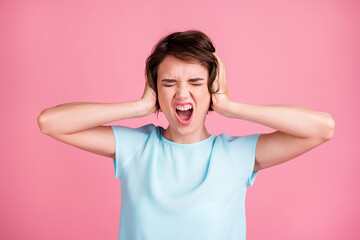 Photo of stressed annoyed woman wear casual blue t-shirt arms cover ears closed eyes isolated pink...