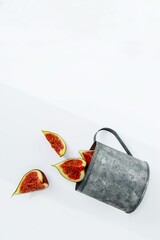 Bright red ripe figs in a metal mug on a white background.
