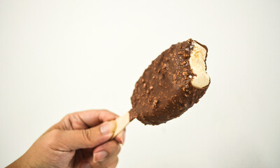 Hand holding ice cream stick.Vanilla flavoured ice cream fully wrapped in a coating of...