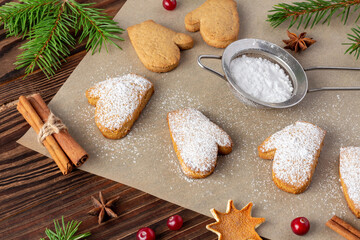 Christmas biscuits on baking paper with powdered sugar and cinnamon sticks close-up