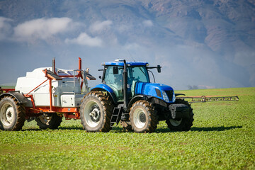 Wide angle image of a crop spray machine spraying chemicals on wheat crop on a farm in south africa