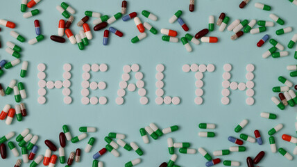 On table there is an inscription health around pills. Health drug development concept