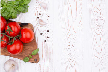 Top view fresh basil, garlic and tomatoes on a rustic white table, flat lay, copy space.