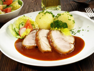 Schweinebraten mit Kartoffelknödel knusprig gebraten auf einem Teller