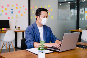 Fototapeta premium Asian workers in offices wear face masks to prevent the spread of COVID-19. Working in the new normal era and Social distance.