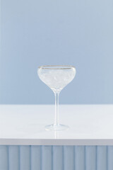 Cocktail glass wineglass with silver golden border on a bar counter on a white blue background