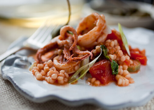 Close up of calamari with tomato, caperberries and pine nuts