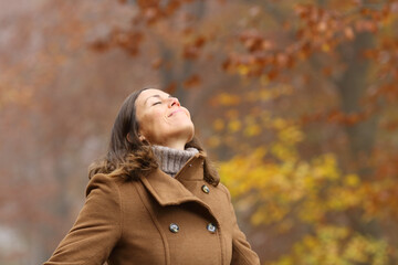 Middle aged woman breathing fresh air in a forest in autumn