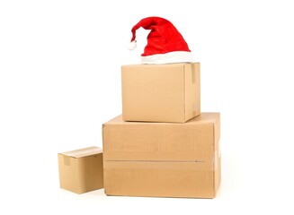 Stack of brown carton cardboard boxes with red santa hat over white background, christmas shopping...
