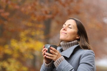 Relaxed middle age woman with coffee breathing in fall