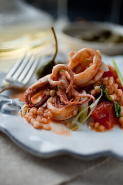 Close up of calamari with tomato, caperberries and pine nuts