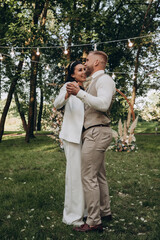 Newlyweds dance and have fun in nature. Walking the bride and groom outdoors. Beautiful summer photo session.