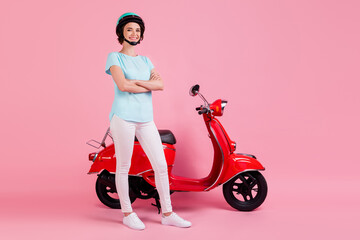 Obraz na płótnie Canvas Full size photo of optimistic nice girl stand moped crossed arms wear white trousers footwear blue slam t-shirt isolated on pink background