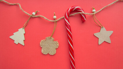 Cute wooden Christmas toys and Santa Claus staff hang on a rope, on a festive red background, Christmas decoration