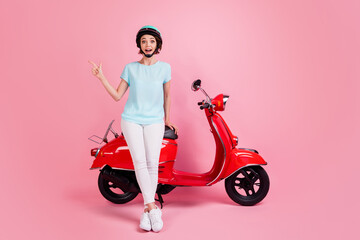 Fototapeta na wymiar Full size photo of amazed pretty lady stand moped point empty space wear trousers footwear slam t-shirt isolated on pink background