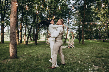 Fototapeta premium Newlyweds dance and have fun in nature. Walking the bride and groom outdoors. Beautiful summer photo session.