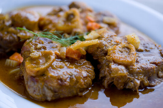 Close up of cooked meat with onion and carrot on platter