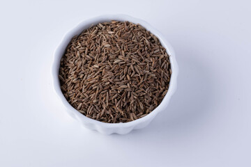 Cumin in a white ceramic cup on a white background