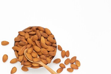 Almond nuts in white bowl with wooden spoon on isolate white background,vegetarian food,top view,flat lay,top down,selective focus.