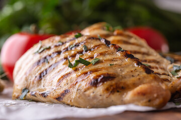 Grilled chicken breast on butcher board close up