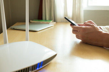 Men hand using smartphone device to connect to wifi network from internet router. Broadband high...