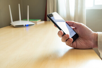 Men hand using smartphone device to connect to wifi network from internet router. Broadband high...
