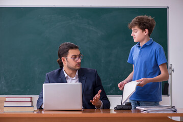 Young male teacher and schoolboy in the classroom