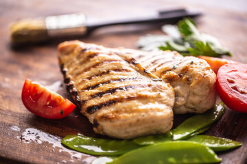 Grilled chicken breast with sweet peas on butcher board
