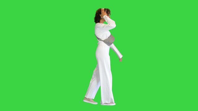 Beautiful sporty african girl listening music in headphones while walking on a Green Screen, Chroma Key.